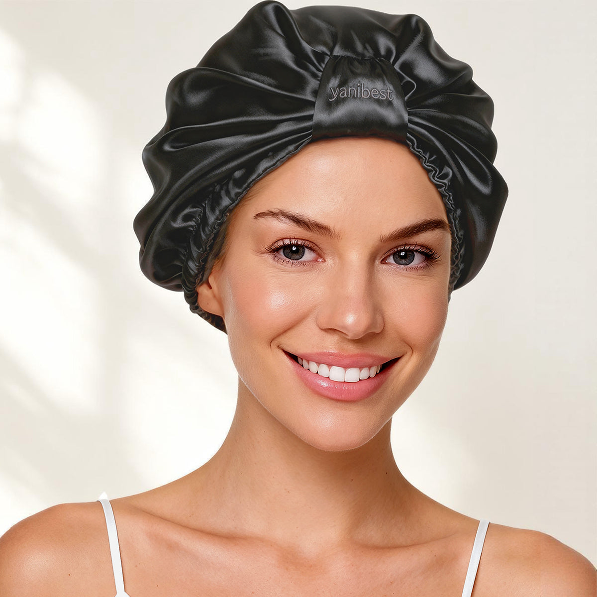 Smiling woman wearing the YANIBEST black 22 Momme mulberry silk turban bonnet for overnight hair protection
