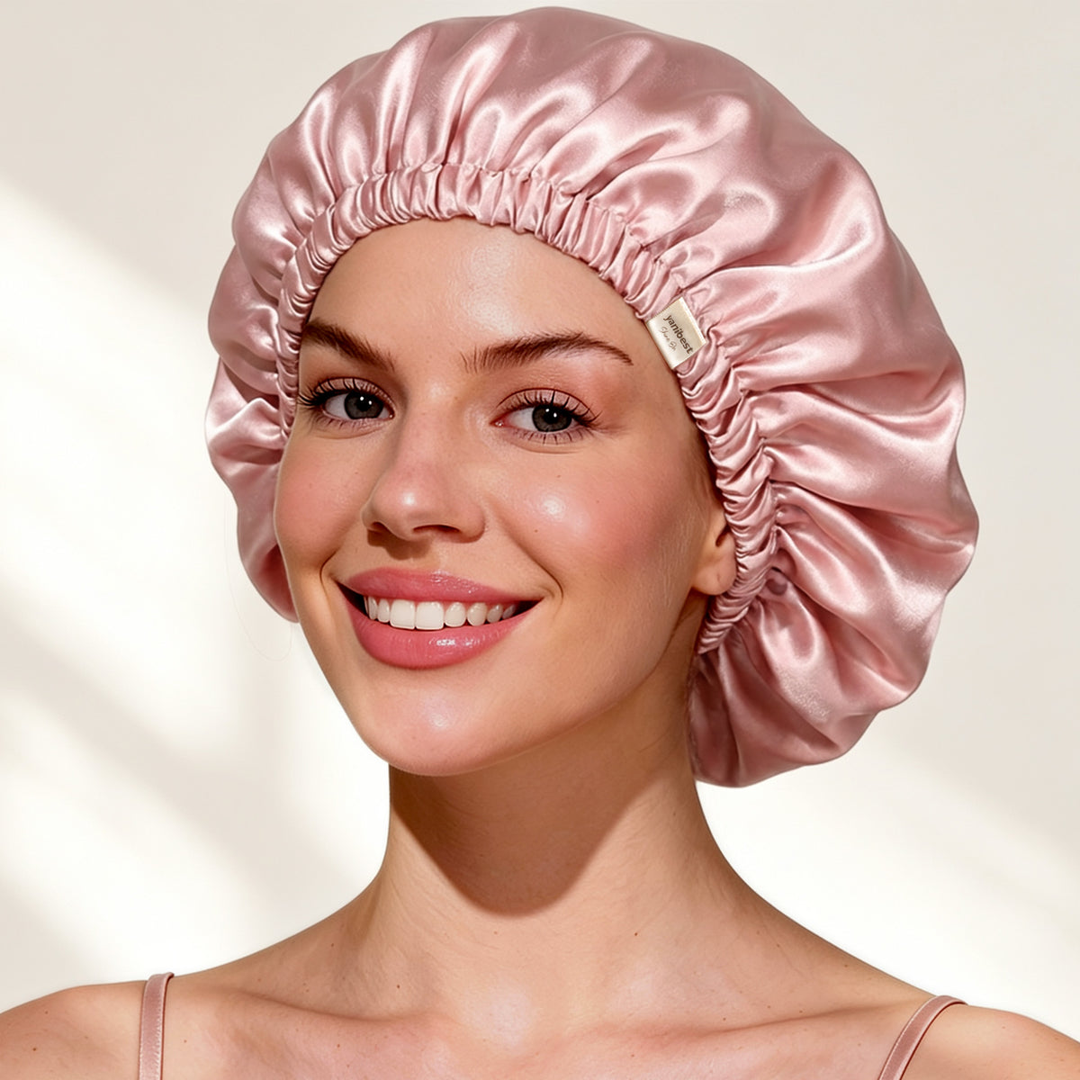 Smiling woman wearing the pink adjustable mulberry silk bonnet in a cozy indoor setting