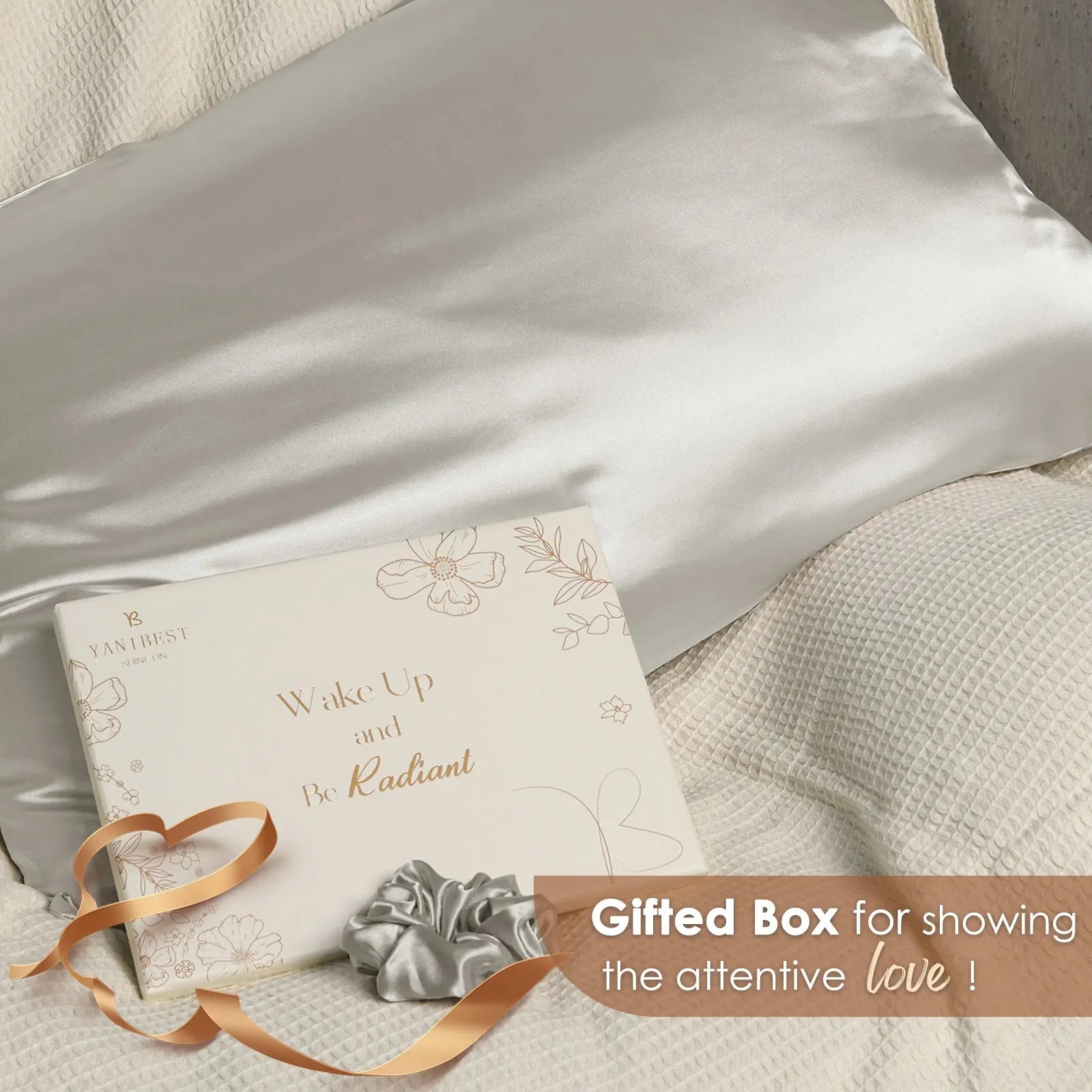 Silver gray satin pillowcase with gift box and matching scrunchie on beige bedding.