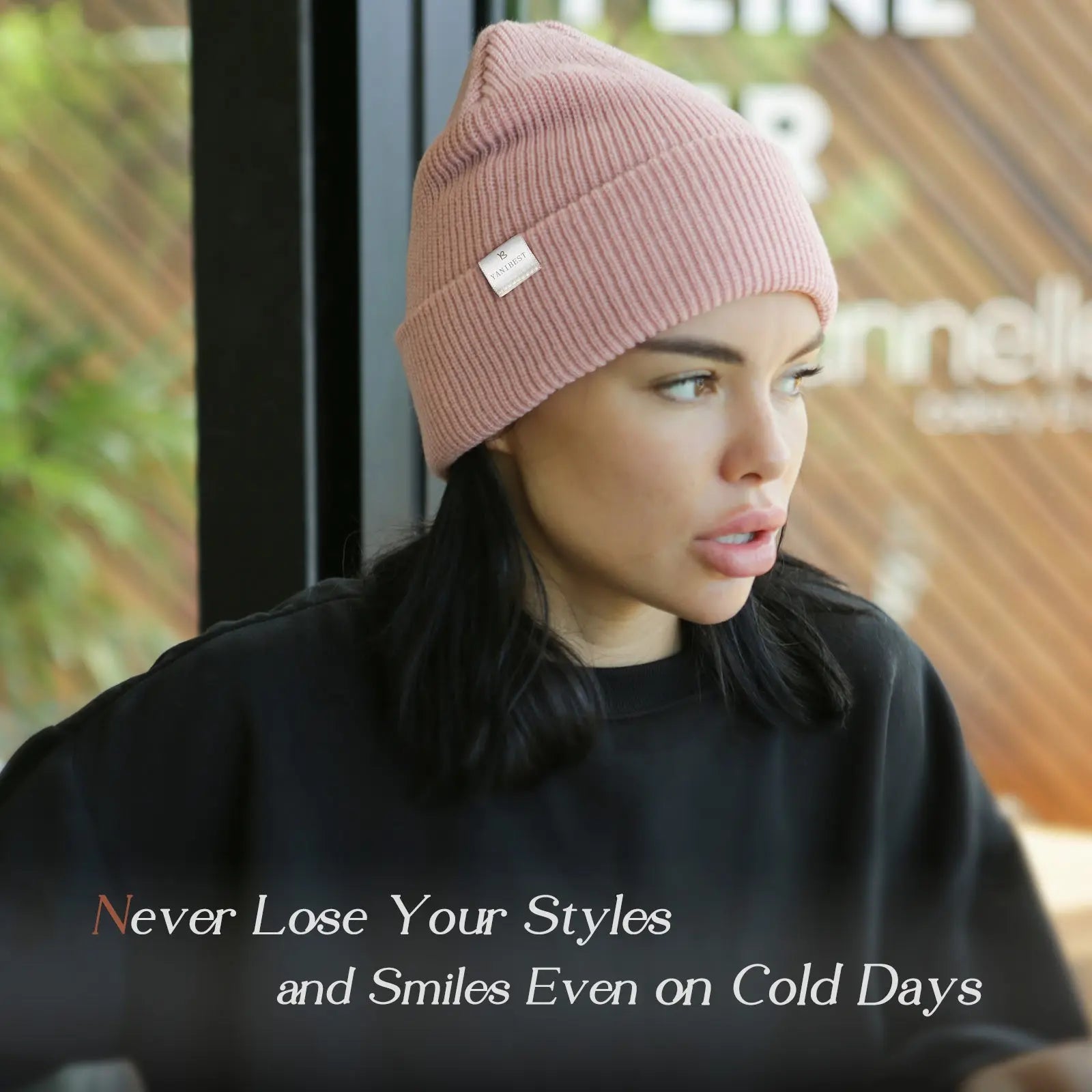 Woman wearing a rose pink satin-lined cuffed beanie hat indoors, showcasing winter fashion.