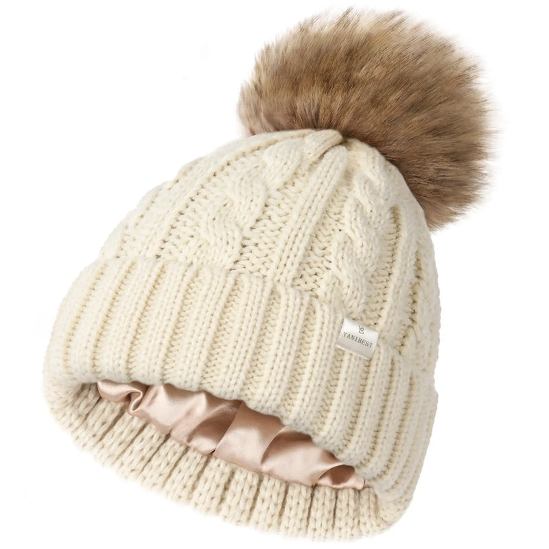 Cream cable knit winter beanie with satin lining and faux fur pom pom on top