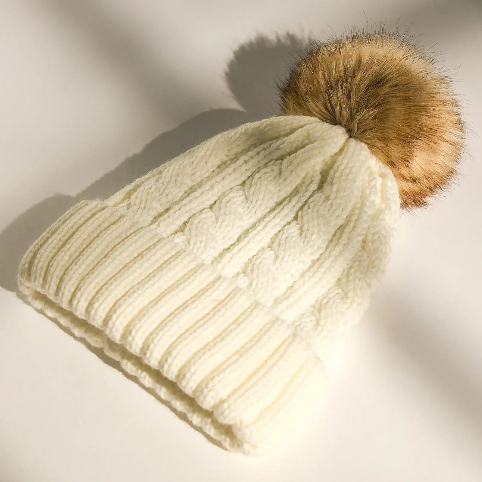 Cream white cable knit winter beanie with faux fur pom pom, satin-lined interior