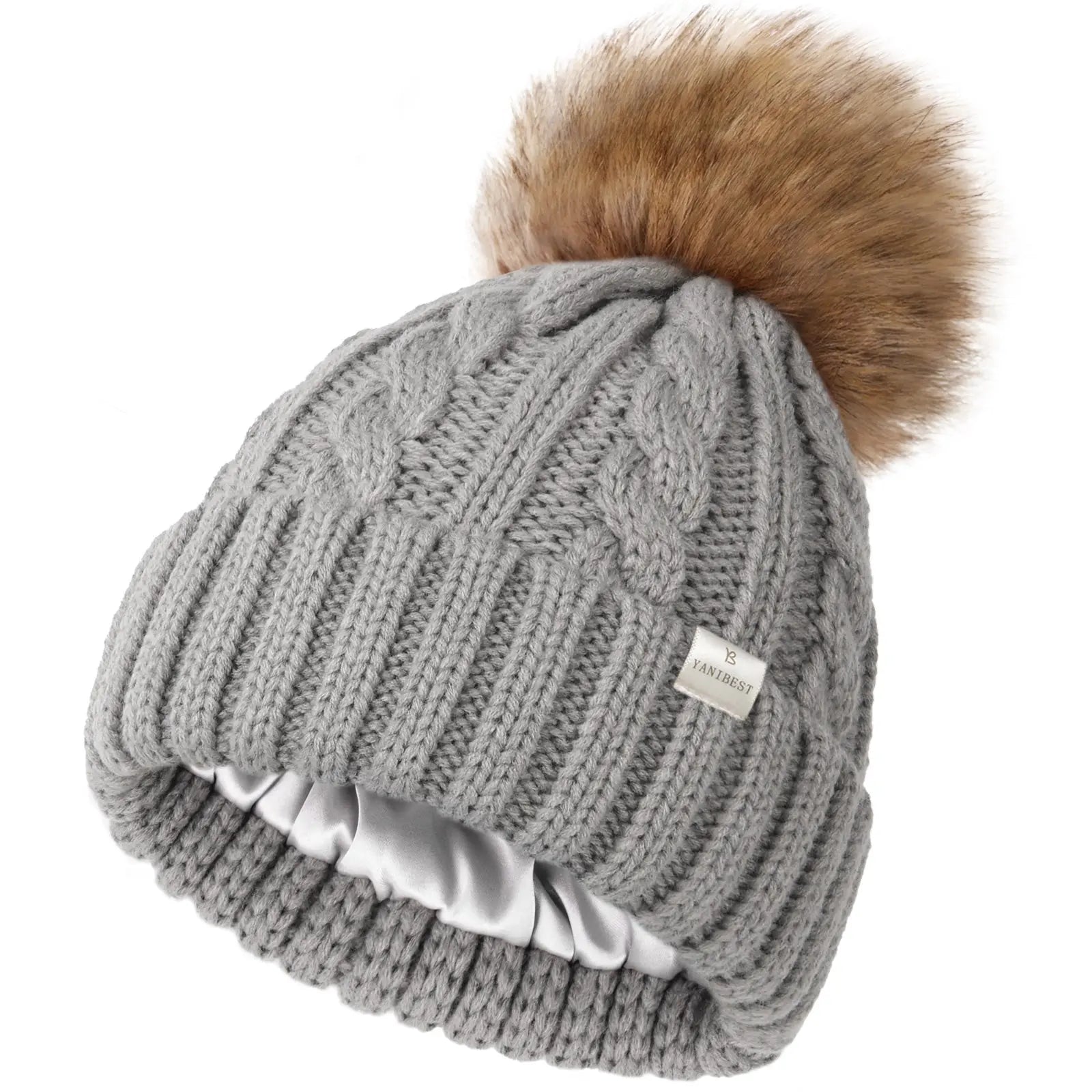 Gray cable knit beanie with faux fur pom and satin lining for winter hair protection